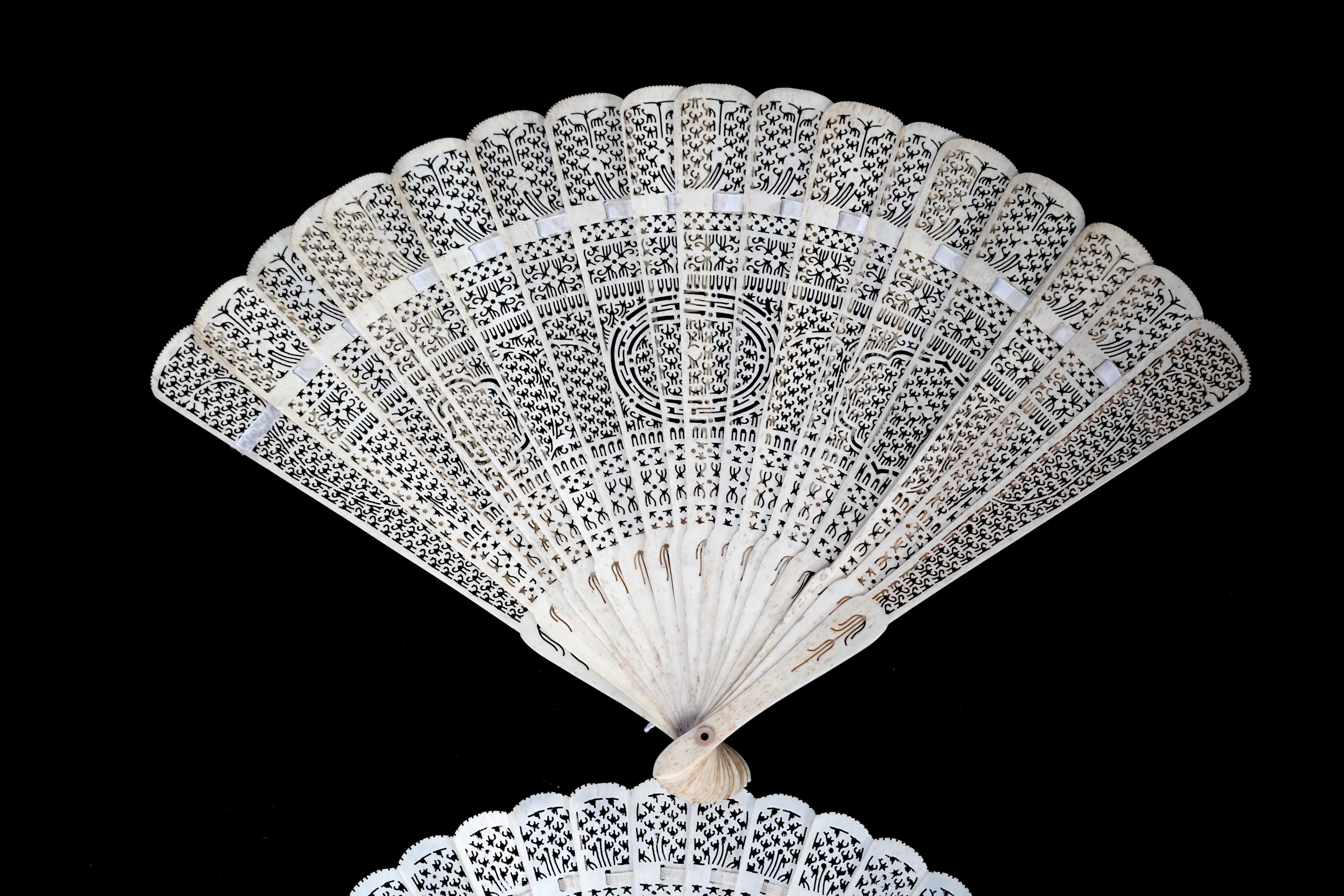 A mid 19th century Chinese brisé bone fan with intricate carving and a later smaller similar fan